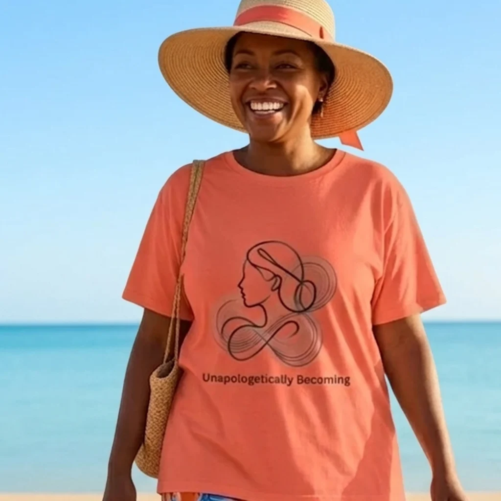 An older African American woman wearing Nourivra Co. original colored graphic tee design of Unapologetically Becoming orange crew neck shirt